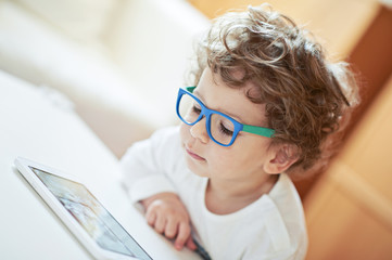 Cute boy in white t-shirt, wearing glasses, watching fairy tale