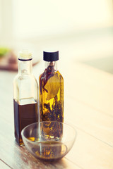 close up of two olive oil bottles and bowl of oil