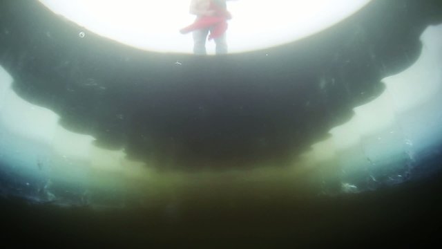 Underwater view of the man having bath in an ice hole