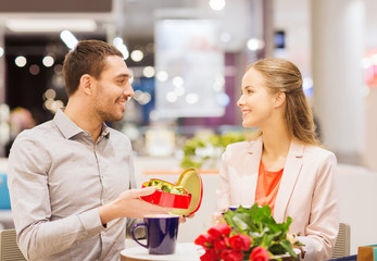 happy couple with present and flowers in mall