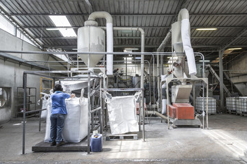 Worker operating in industrial machinery for plastic waste processing in recycling facility. Garbage, environment, management, sustainability, factory, green, industry, processing, ecology, treatment