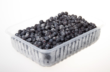 Frozen blueberries in a plastic container on a white background.