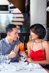 Asian couple drinking cocktails in fancy bar