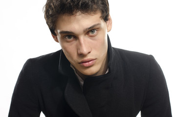 Portrait of a beautiful young man dressed in a black long coat,
