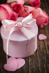 Bouquet of pink roses and gift box on wooden background