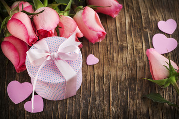 Bouquet of pink roses and gift box on wooden background with cop