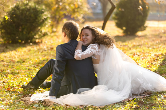 just married couple relaxing on grass at autumn park
