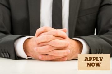 Apply Now Text on Small Wooden Piece in Front Businessman