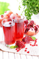 Ripe pomegranates with juice on table on light background