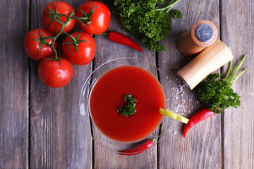 Tomato juice in goblet and fresh vegetables on wooden
