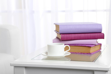 Purple books with cup near sofa