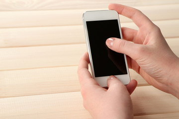 Hands using smart mobile phone on wooden table background