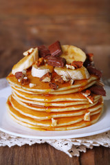 Stack of delicious pancakes with chocolate, honey, nuts and