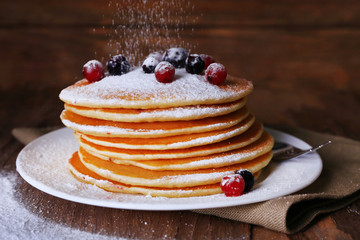 Stack of delicious pancakes with powdered sugar and berries