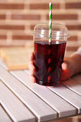Female sitting at wooden table with fast food closed cup of