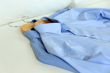 Blue shirts on hanger, on white armchair background