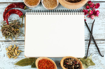Spices with recipe book on color wooden table background