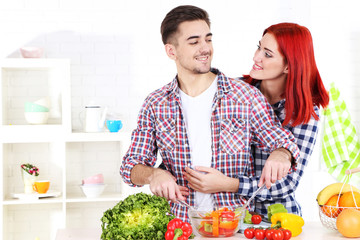 Happy couple preparing  vegetable salad in kitchen