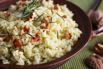 Rice with walnuts and rosemary in plate on bamboo mat