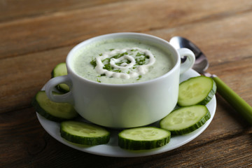 Cucumber soup in bowl on rustic wooden table background