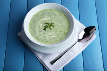 Cucumber soup in bowl on color wooden planks background