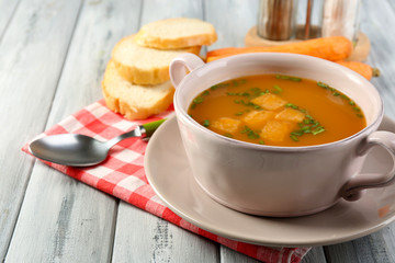 Carrot soup, cream and spoon, on  color wooden background