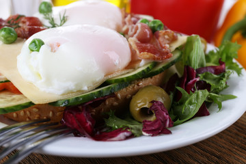 Sandwich with poached eggs, bacon and vegetables