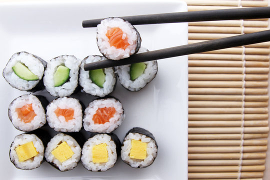 Chopsticks holding sushi from assorted sushi meal