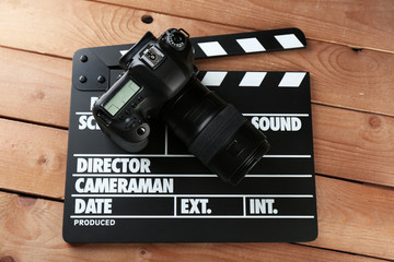 Photo camera and movie clapper on wooden background