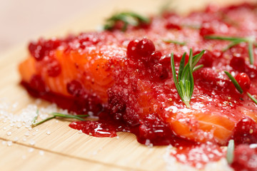 Salmon steak bein marinated in salt with rosemary and redberries