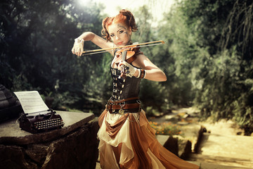 Attractive young woman playing on violin outdoors.