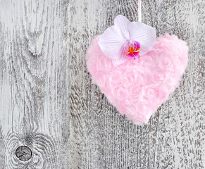 Fur pink heart with a flower orchid on wooden background
