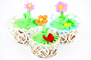 Fototapeta na wymiar three spring flowers muffin cakes on white