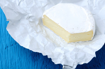 Camembert cheese on a blue wooden background