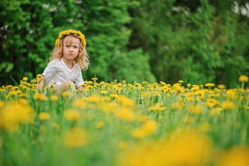 adorable child girl in wreath portrait on spring dandelion field