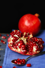 Juicy ripe pomegranates on wooden table, on dark background