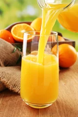 Rolgordijnen Pouring orange juice from glass carafe, © Africa Studio