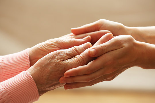 Old and young holding hands on light background