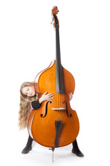 young blond girl looks from behind double bass in studio
