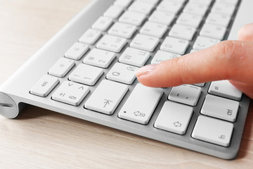 Female hand with keyboard on wooden desktop background