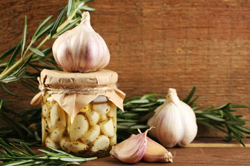 Canned garlic in glass jar on wooden background