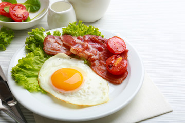 Bacon and eggs on color wooden table background