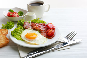 Bacon and eggs on color wooden table background