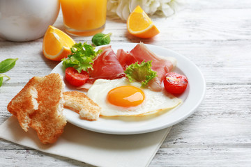 Bacon and eggs on color wooden table background.