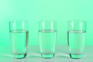 Glasses of water on table and colorful background