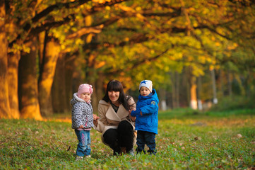 Fototapeta premium mother with children twins on a walk in the autumn park