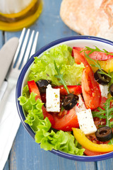salad in bowl with bread and oil on blue background