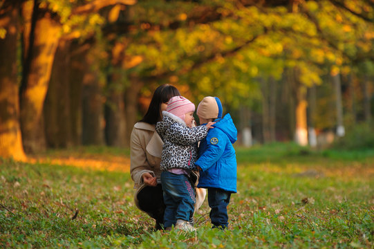 Mother With Children Twins On A Walk In The Autumn Park