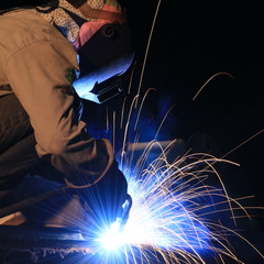 worker with protective mask welding metal