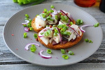canapes with herring on a white plate